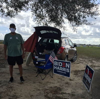 poll greeter with car and signs